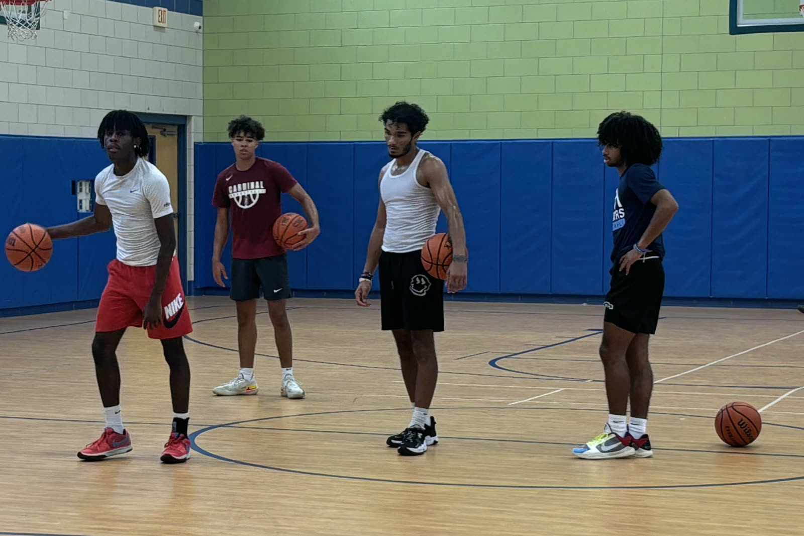 High school players with basketballs at a Baseline Hoops training session