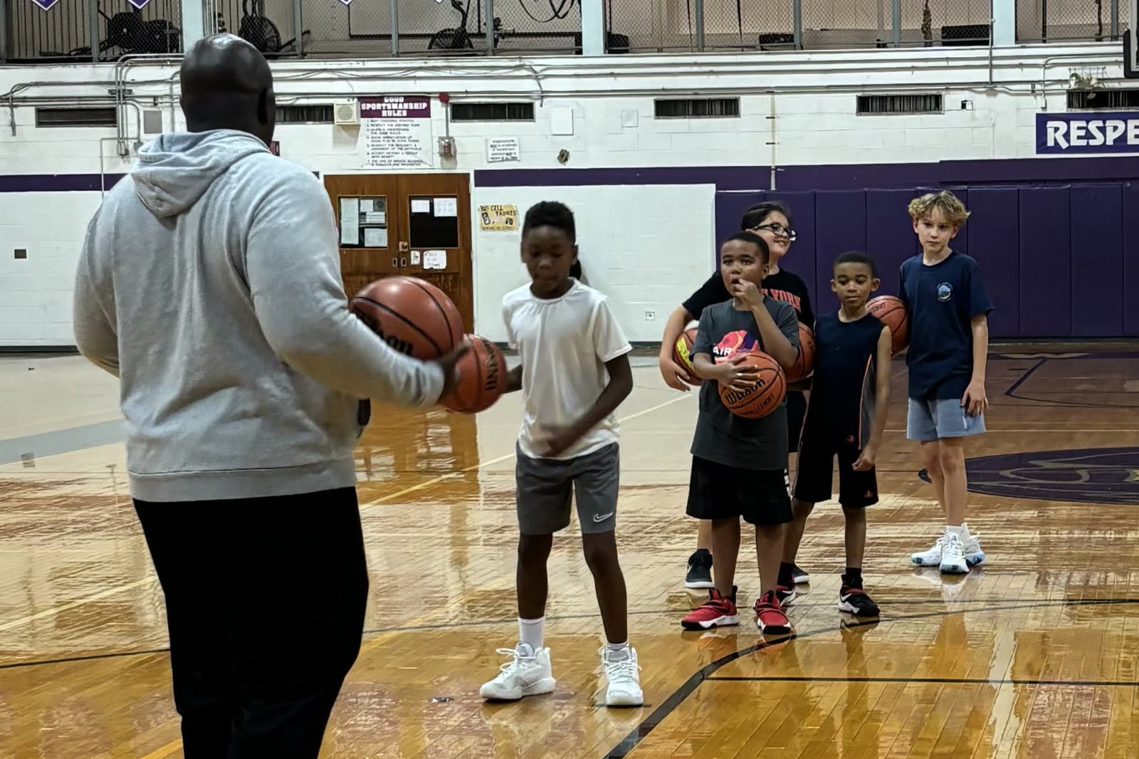 Coach demonstrating a ball-handling move to young players at group training